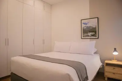 a white bedroom with a bed and a night stand at Seaside Apartment near Malecon Miraflores by Wynwood House in Lima