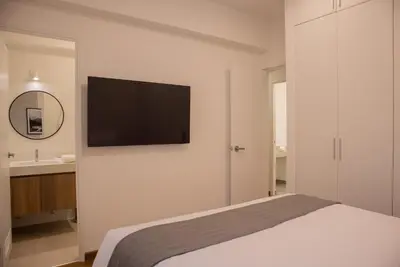 a bedroom with a bed and a television on a wall at Seaside Apartment near Malecon Miraflores by Wynwood House in Lima