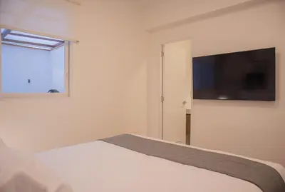 a bedroom with a bed and a flat screen tv at Seaside Apartment near Malecon Miraflores by Wynwood House in Lima