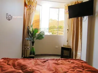a bedroom with a bed and a television and a window at Hotel Fortaleza in Chasquitambo
