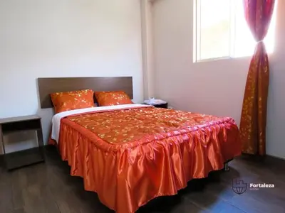 a bedroom with a bed with an orange comforter and a window at Hotel Fortaleza in Chasquitambo