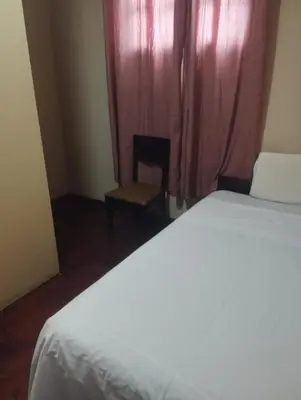 a bedroom with a bed and a chair and a window at Hospedaje el señorial in Lima