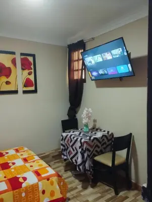 a room with a table and a tv on the wall at Hospedaje el señorial in Lima