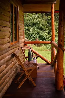 a porch of a log cabin with a table and chair at Montecatini Ecolodge in Oxapampa