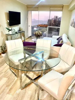a living room with a glass table and white chairs at Lovely apartment in front of malecon! in Lima