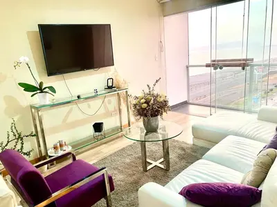 a living room with a couch and a table and a tv at Lovely apartment in front of malecon! in Lima