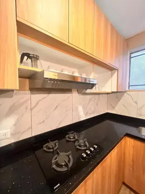 a black stove top in a kitchen with wooden cabinets at Céntrico Dpto Puca Lima a 2 cuadras de Hospital Rebagliati y Real Plaza Salaverry in Lima