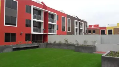 a red building with a green lawn in front of it at Lascondes in Chosica