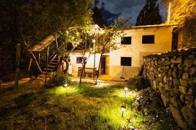a house with lights in the yard at night at Pinkuylluna Lodge in Ollantaytambo
