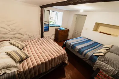 a bedroom with two beds and a dresser in it at Pinkuylluna Lodge in Ollantaytambo