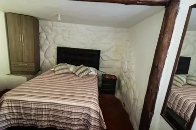 a bedroom with a bed with a stone wall at Pinkuylluna Lodge in Ollantaytambo