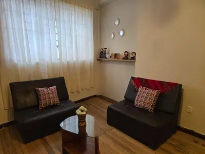 a living room with two leather chairs and a table at Cozy loft in the heart of the city in Cusco