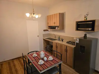 a kitchen with a table with chairs and a refrigerator at Cozy loft in the heart of the city in Cusco