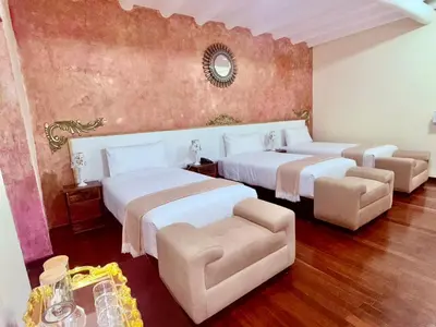 a bedroom with two beds and a chair and a mirror at Ayni Boutique Hotel in Cusco