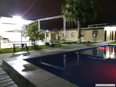 a swimming pool at night with two benches and a building at Casa Grau Chincha in Chincha