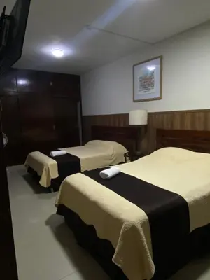 a hotel room with two beds and a television at Casa Grau Chincha in Chincha