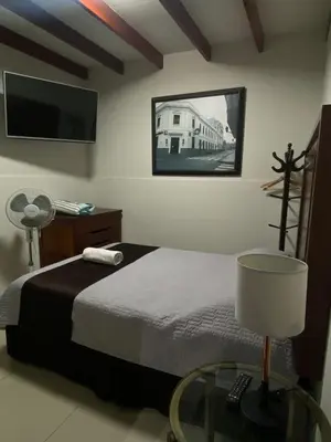 a bedroom with a bed and a table with a lamp at Casa Grau Chincha in Chincha