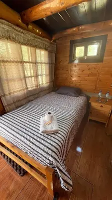 a bedroom with a bed in a wooden cabin at CABAÑAS RANCH OXaPAMP4 in Oxapampa
