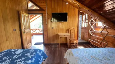a bedroom with a bed and a television in a cabin at CABAÑAS RANCH OXaPAMP4 in Oxapampa