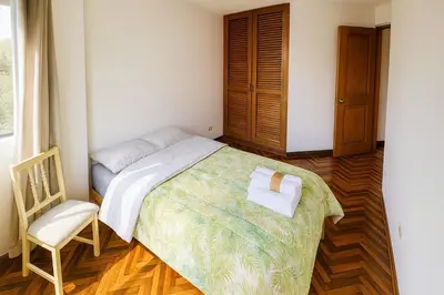 a small bedroom with a bed and a chair at Lima Family Lodge Apartment near Miraflores Center in Lima