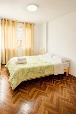 a bedroom with a large bed and a wooden floor at Lima Family Lodge Apartment near Miraflores Center in Lima