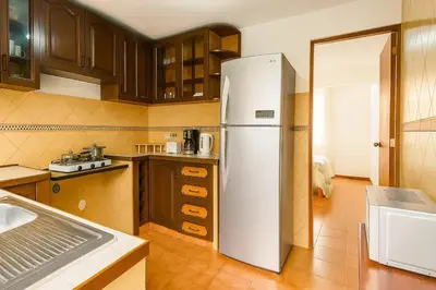 a kitchen with a white refrigerator and wooden cabinets at Lima Family Lodge Apartment near Miraflores Center in Lima