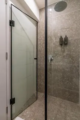 a shower with a glass door in a bathroom at Solar Breezy Retreat by Geko in Lima