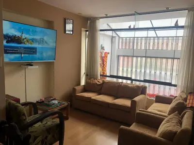a living room with a couch and a large window at Departamento familiar Lucrepata in Cusco