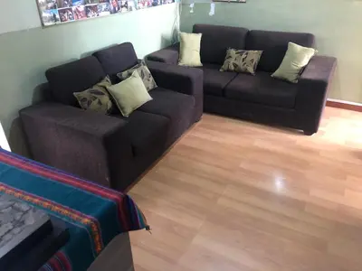 a living room with two black couches and a wooden floor at Departamento familiar Lucrepata in Cusco