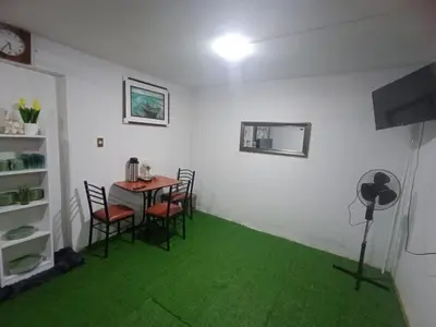 a room with a table and chairs and green carpet at IN FRONT OF THE NEW AIRPORT Hospedaje - A y C Taxi Free - Airport - Apartment on the 1st Floor in Lima