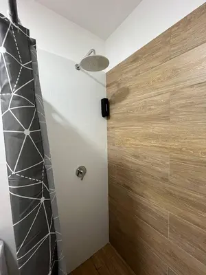 a bathroom with a shower with a wooden wall at Apartamento Amoblado a un paso del parque de las aguas in Lima