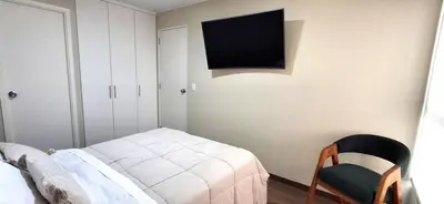 a bedroom with a bed and a tv on the wall at Acogedor departamento 1 dormitorio in Lima