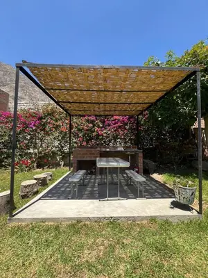 a picnic shelter with a picnic table and benches at La Casita de Condoray - Lunahuana in Lunahuaná