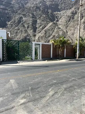 a fence on the side of a street with a mountain at La Casita de Condoray - Lunahuana in Lunahuaná