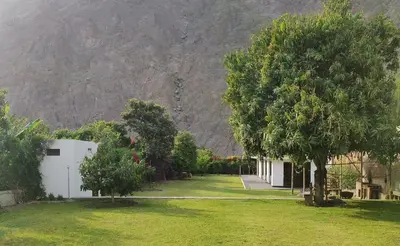 a house with a tree and a mountain in the background at La Casita de Condoray - Lunahuana in Lunahuaná