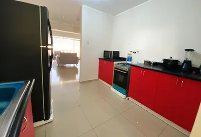 a kitchen with red cabinets and a black refrigerator at Apartment in downtown Huancayo in Huancayo