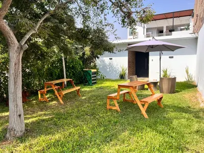 two picnic tables and an umbrella in the grass at Casa Rosé Vacacional in Santa Rosa