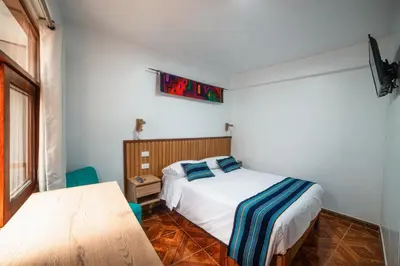 a small bedroom with a bed and a table at Casa Andora in Machu Picchu
