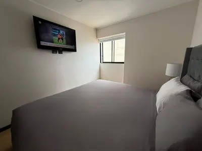 a bedroom with a bed and a tv on the wall at Departamento Style in Lima