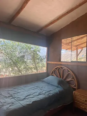 a bedroom with a bed and two windows at Casa Divina Medicina in Urubamba
