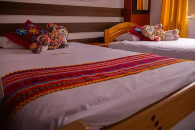 two beds with white sheets with colorful blankets on them at Mirador All Sur Cusco in Cusco