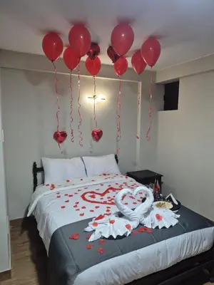 a bed with red balloons hanging from the ceiling at Hotel Naciones Unidas in Lima