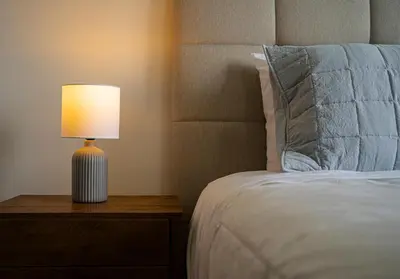 a bed with a lamp on a table next to it at Duplex Moderno y Espacioso en Miraflores in Lima