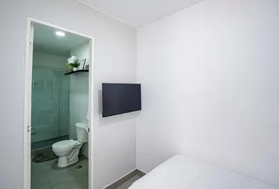 a white bathroom with a toilet and a tv on the wall at Duplex Moderno y Espacioso en Miraflores in Lima