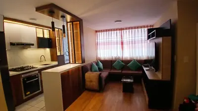 a living room with a couch and a kitchen at Departamento amoblado y Estacionamiento Gratis in Lima