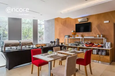a dining room with tables and chairs and a tv at Ramada Encore by Wyndham Lima San Isidro in Lima