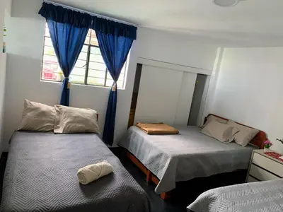 a bedroom with two beds and a window with blue curtains at HOSPEDAJE don VICTOR