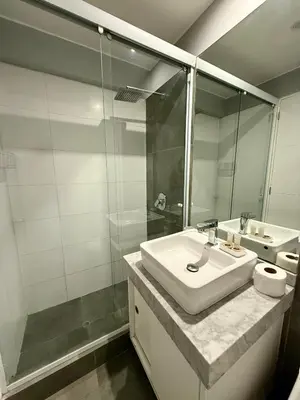 a white bathroom with a sink and a shower at Departamento Osma in Lima