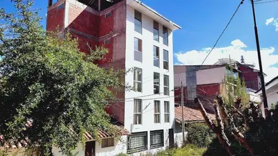 a white and red building next to a tree at Apartamento en Cusco IV in Cusco