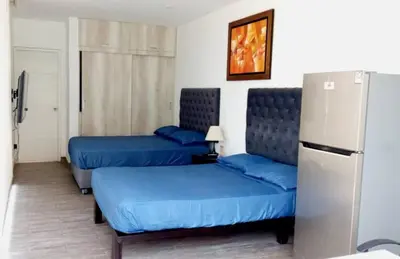 a room with two blue beds and a refrigerator at Maya House Cieneguilla in Cieneguilla